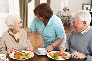 nurse with elderly man and woman eating