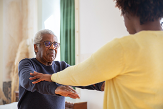 nurse helping elderly man with excersize